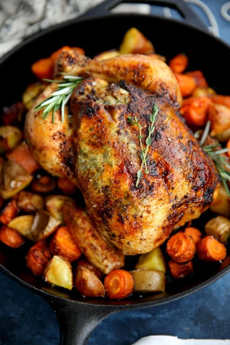 Perfectly roasted whole chicken on a rustic wooden table.