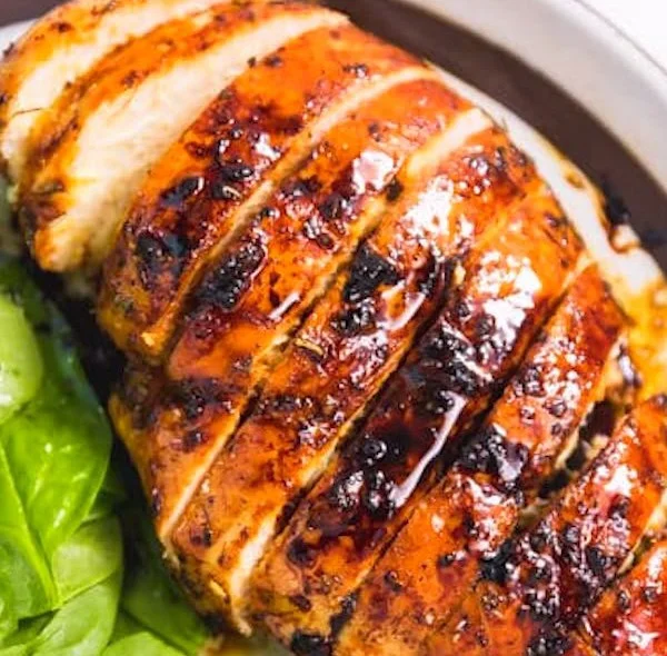 Baked Balsamic Chicken Breast garnished with herbs on a plate.