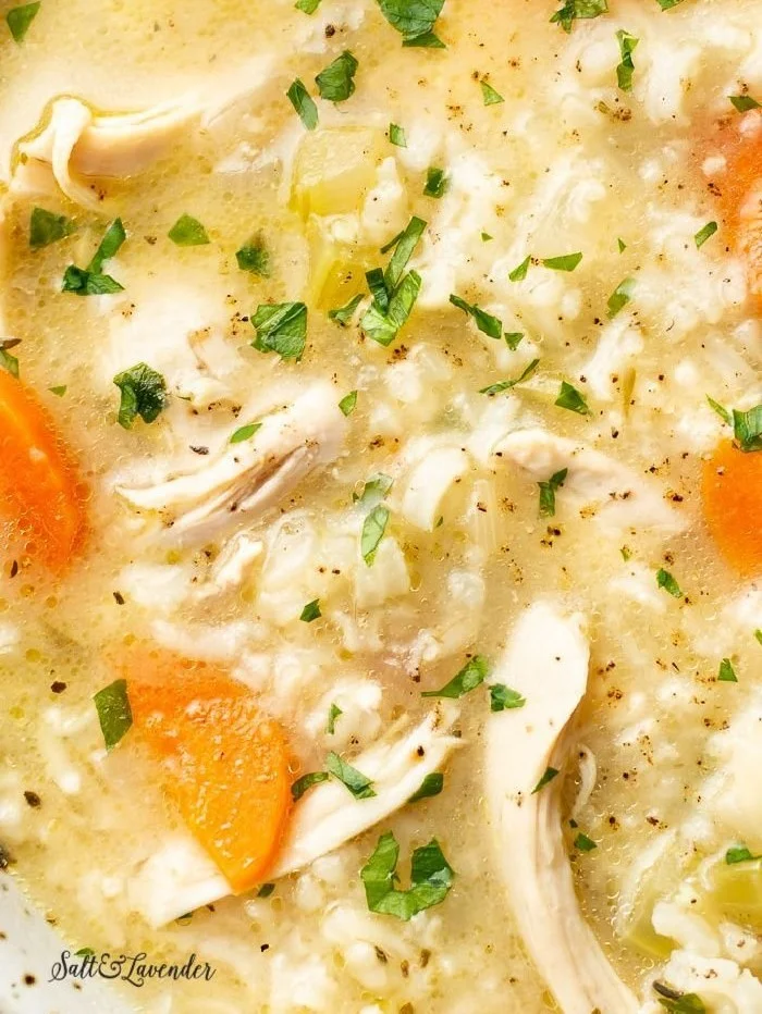Bowl of homemade chicken rice soup with vegetables and herbs.