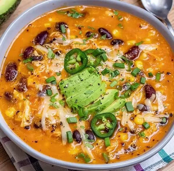 Bowl of chicken enchilada soup topped with cheese and cilantro