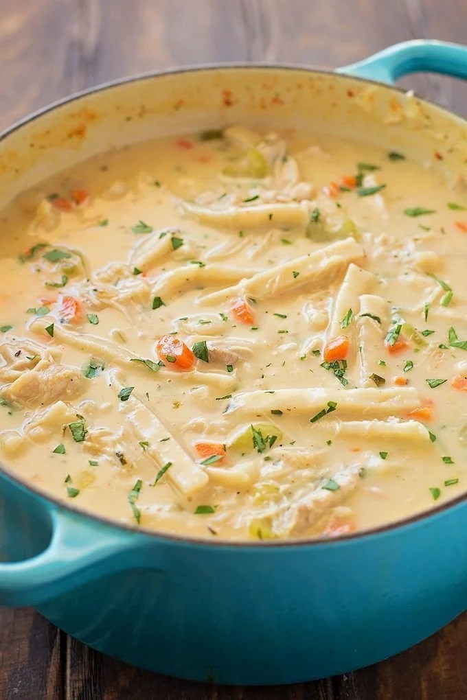 Bowl of creamy chicken noodle soup with vegetables and herbs
