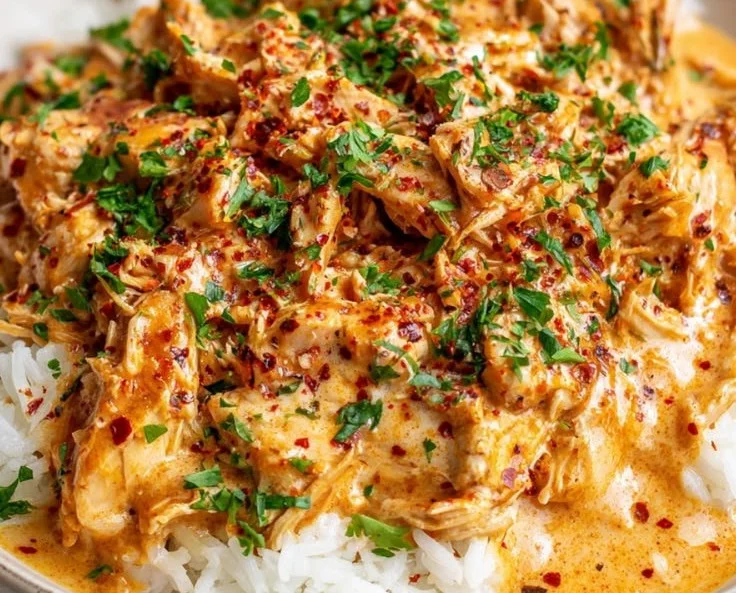 Creamy Crockpot Cajun Butter Chicken in a bowl with herbs and spices