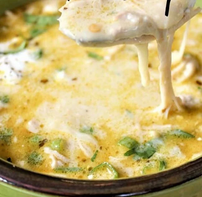 Bowl of creamy green enchiladas chicken soup topped with cilantro and cheese