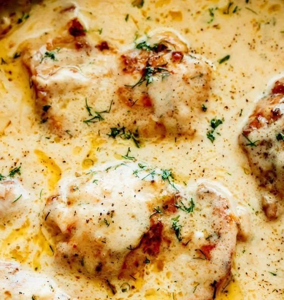 Creamy oven baked chicken thighs served on a plate garnished with herbs