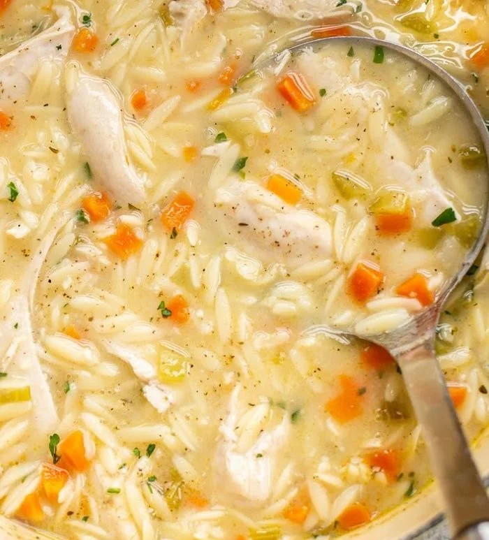 Bowl of easy lemon chicken orzo soup garnished with herbs and lemon slices
