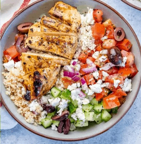 A vibrant Greek Chicken Bowl with marinated chicken, fresh veggies, and tzatziki sauce