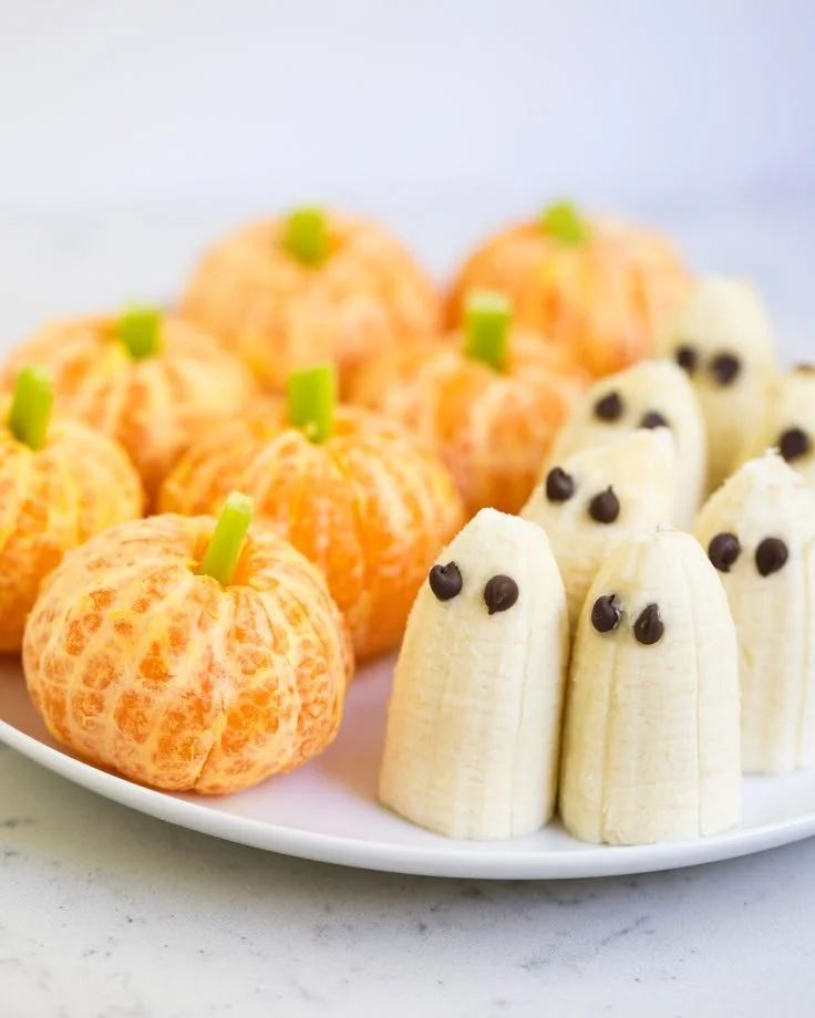 Variety of healthy Halloween snacks including spooky fruit and veggie treats.