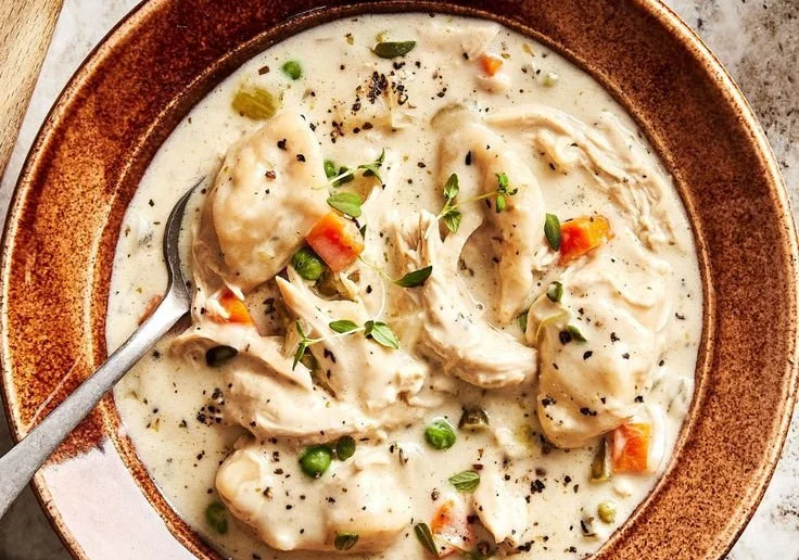 Bowl of hearty dairy-free chicken dumpling soup garnished with herbs
