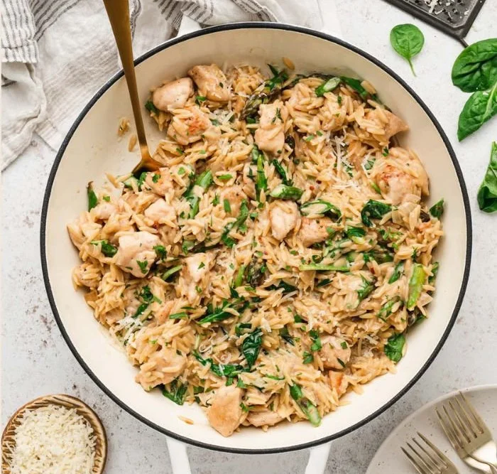 High protein chicken orzo served in a bowl with fresh herbs and vegetables