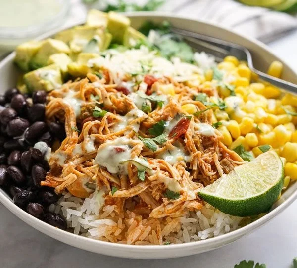 Slow cooker chicken burrito bowl topped with fresh ingredients and toppings.