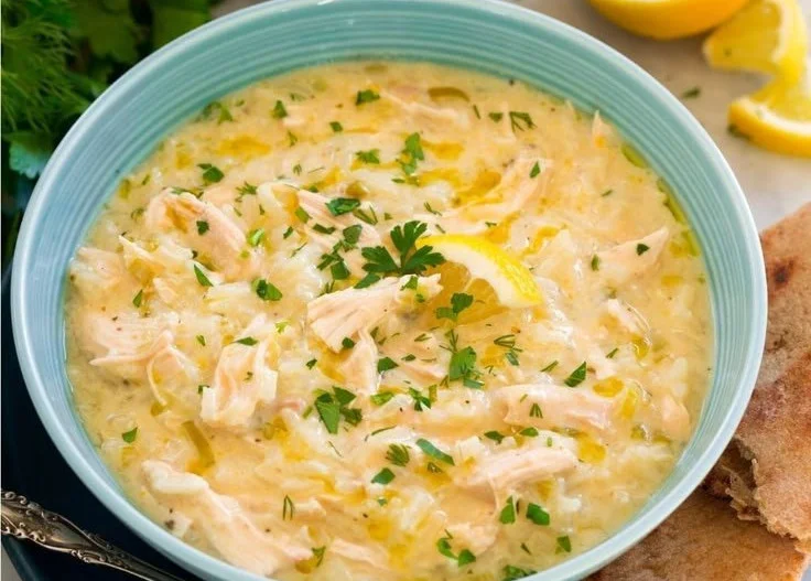 Bowl of avgolemono soup garnished with lemon and herbs, showcasing Greek cuisine.
