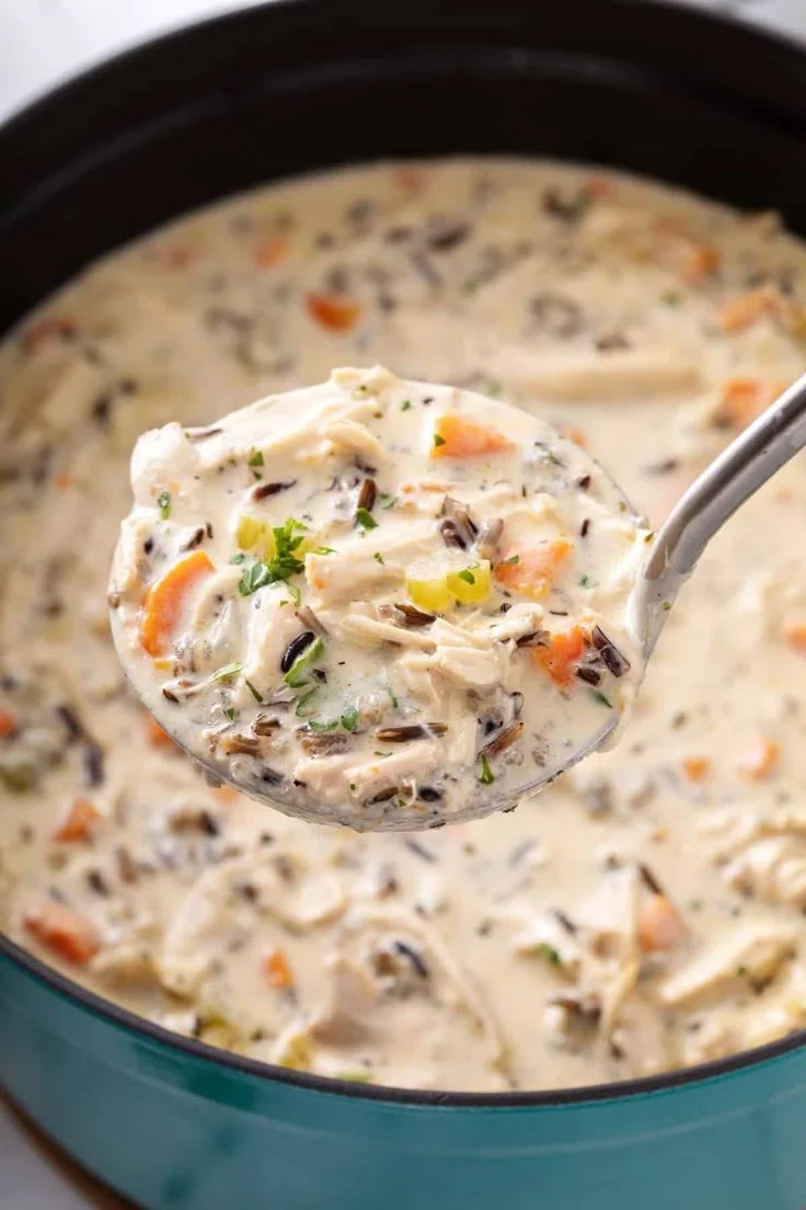Bowl of Chicken and Wild Rice Soup garnished with herbs and served with bread.
