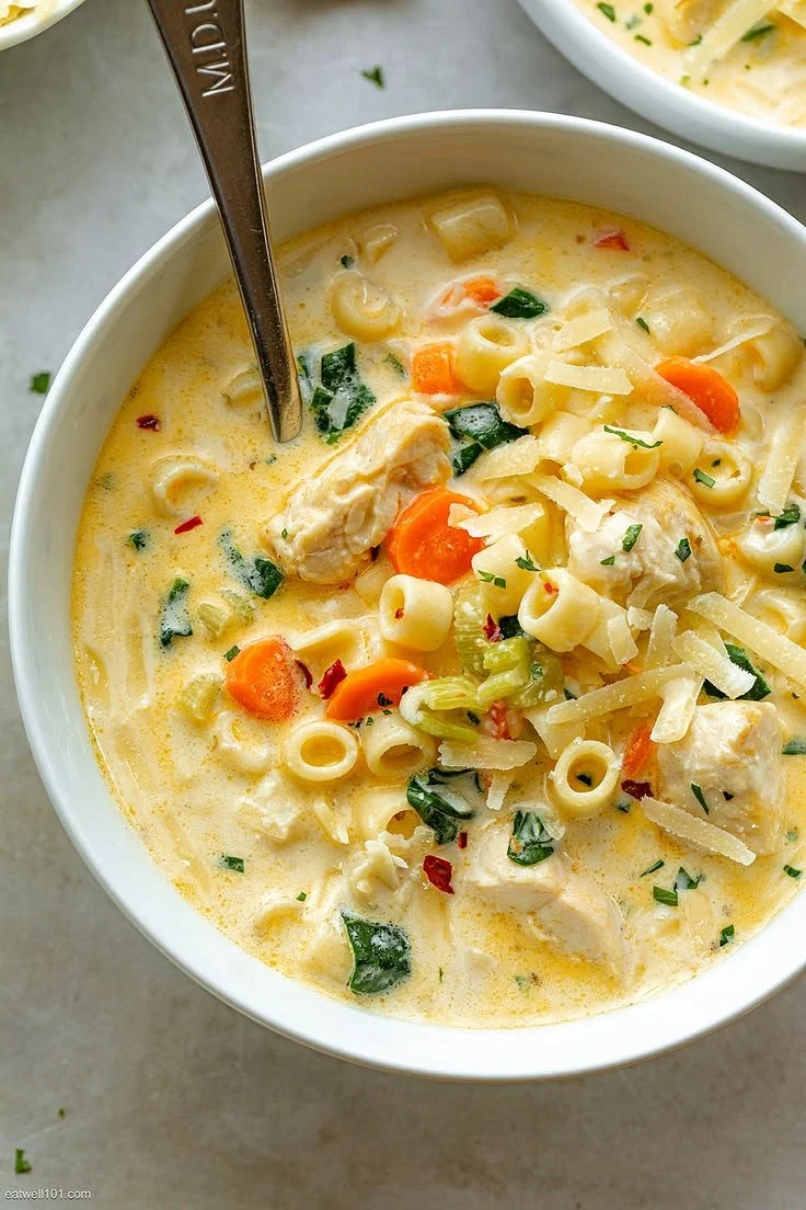 Creamy chicken pasta soup with carrots and spinach in a bowl