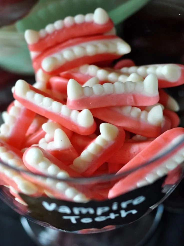 Apothecary jar filled with vampire teeth candy for Halloween party treats.